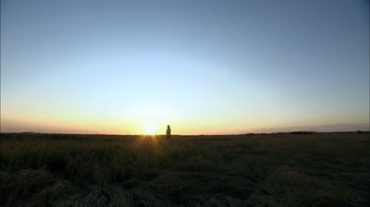 一个人在平原上行走越过夕阳视频素材