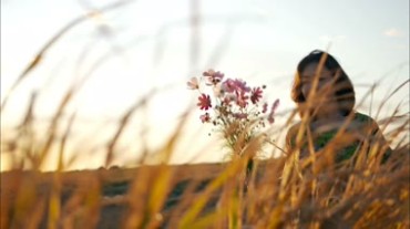 阳光下的田野，浪漫梦幻女孩拿花艺术镜头视频素材