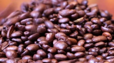 烘培后表面油亮棕色咖啡豆倒进桌面散落滑动特写高清实拍视频素材