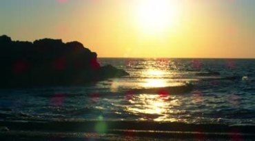 沙滩上的日落夕阳下的海浪轻轻拍打礁石美景视频素材