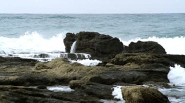 海岸边的岩石海浪拍打礁石激起浪花实拍视频素材