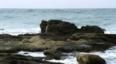 海岸边的岩石海浪拍打礁石激起浪花实拍视频素材